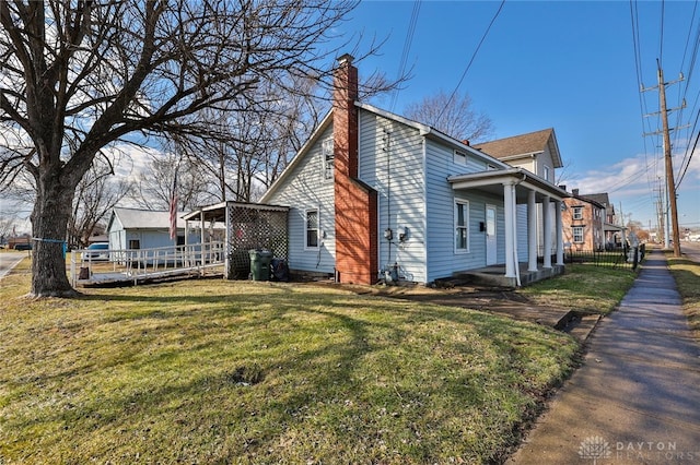 view of side of property with a chimney, fence, and a lawn