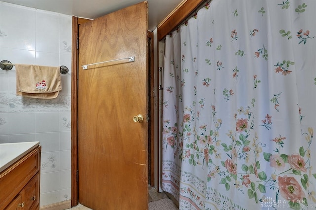 full bathroom featuring curtained shower, vanity, and tile walls