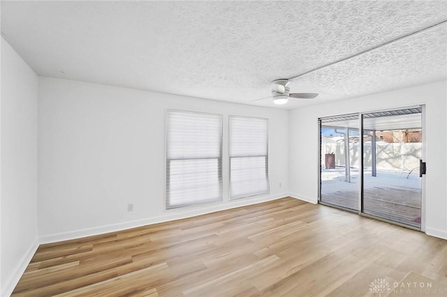 spare room with light wood-style floors, ceiling fan, baseboards, and a textured ceiling