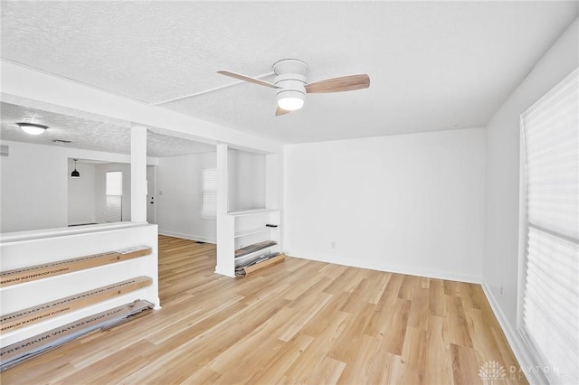 unfurnished room with a textured ceiling, ceiling fan, wood finished floors, and baseboards