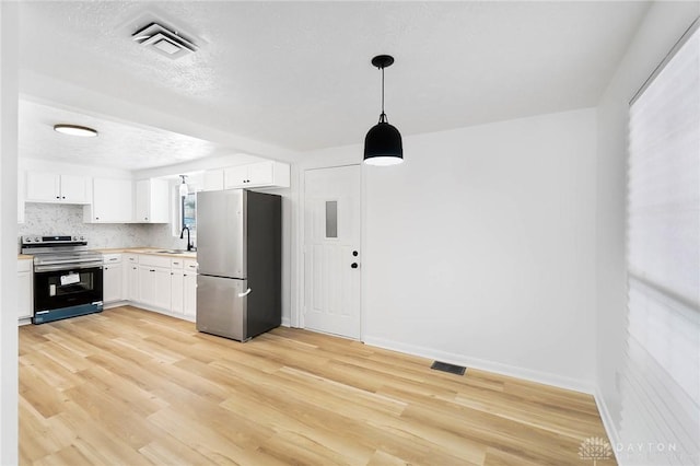 kitchen with a sink, visible vents, white cabinets, hanging light fixtures, and appliances with stainless steel finishes