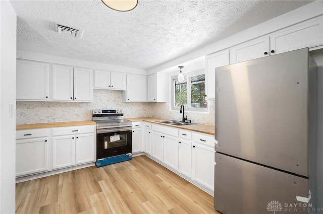 kitchen with stainless steel appliances, a sink, wood counters, and white cabinets