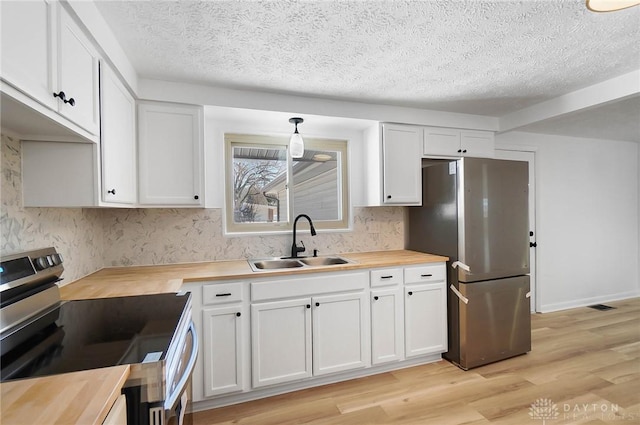 kitchen with hanging light fixtures, wood counters, white cabinets, and stainless steel appliances