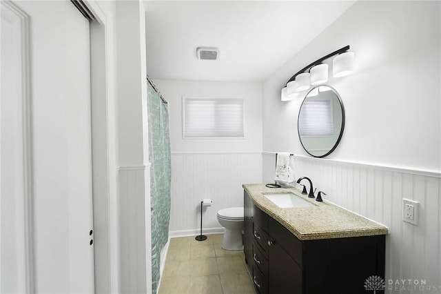 bathroom featuring tile patterned flooring, wainscoting, vanity, and toilet