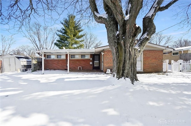 view of front of home with brick siding, fence, and a shed