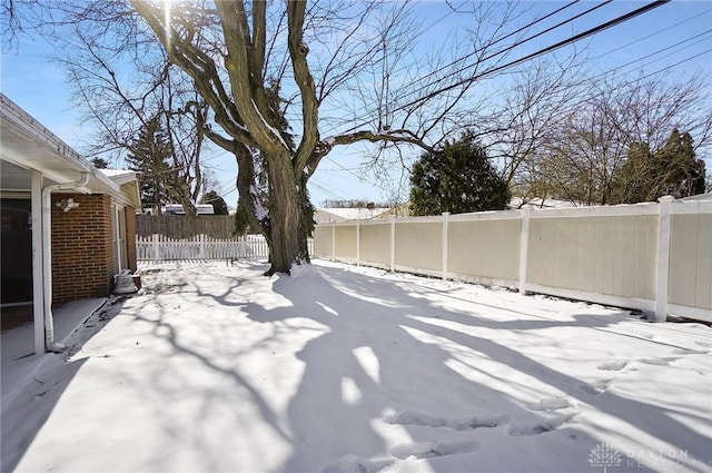 snowy yard featuring a fenced backyard