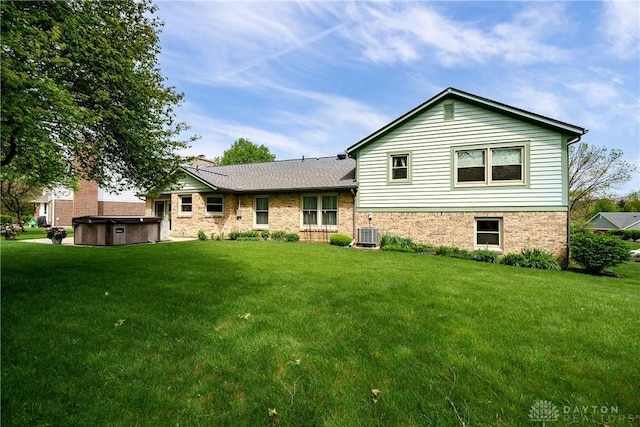 rear view of house with a lawn, central AC unit, and a hot tub