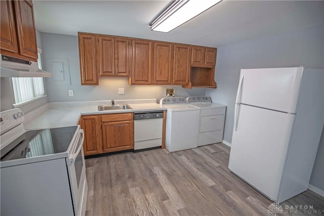 kitchen with light countertops, washing machine and dryer, a sink, white appliances, and under cabinet range hood