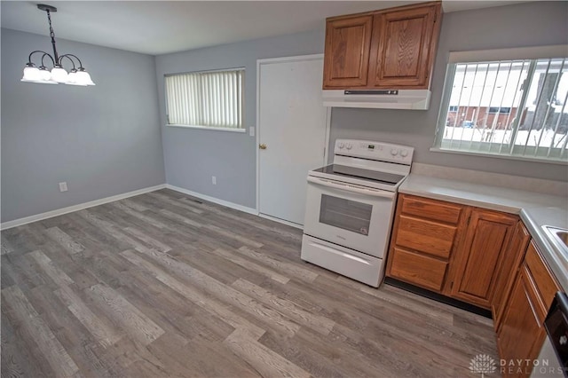 kitchen with brown cabinets, white electric range oven, under cabinet range hood, and light countertops