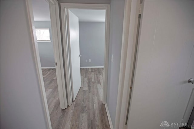 hallway featuring light wood-style flooring and baseboards