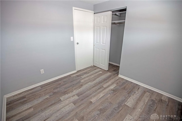 unfurnished bedroom with a closet, baseboards, and wood finished floors