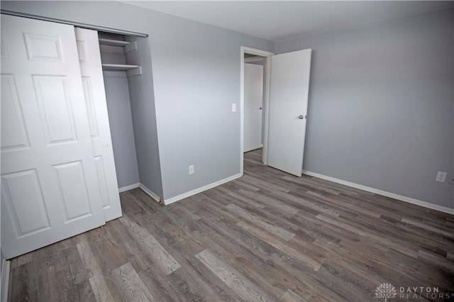 unfurnished bedroom with a closet, baseboards, and wood finished floors