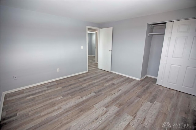 unfurnished bedroom featuring a closet, light wood-style flooring, and baseboards