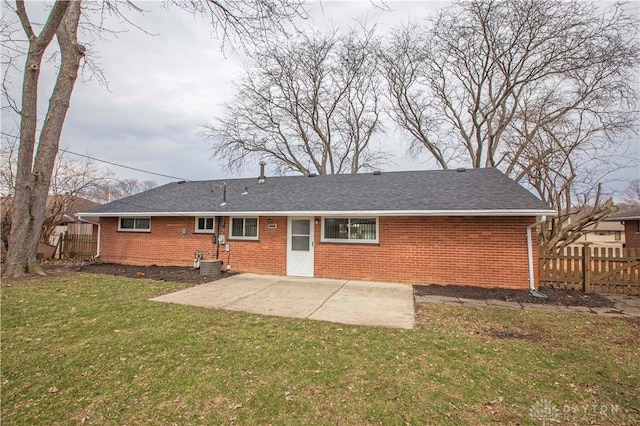 rear view of property with a yard, brick siding, a patio area, and fence