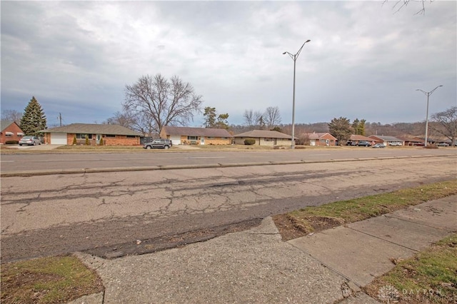 view of road with a residential view, sidewalks, and street lights