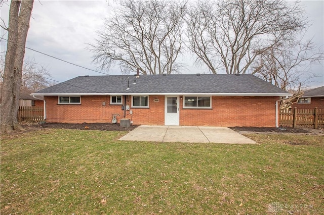 rear view of property with brick siding, a lawn, and a patio area