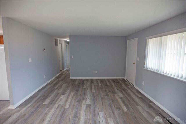 unfurnished living room with visible vents, dark wood finished floors, and baseboards