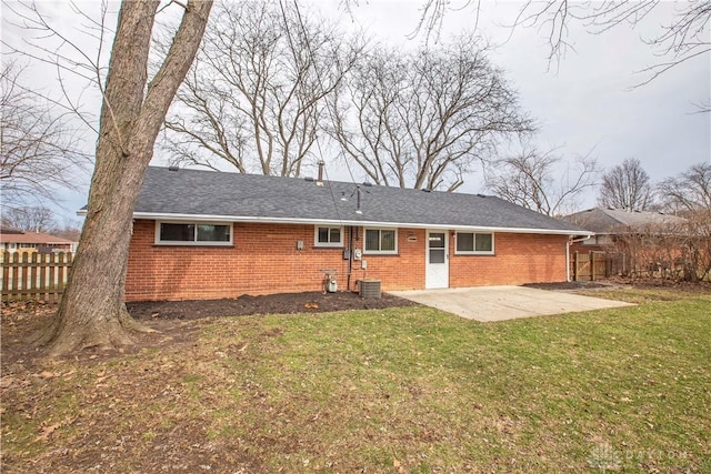 rear view of house featuring a yard, brick siding, a patio, and fence