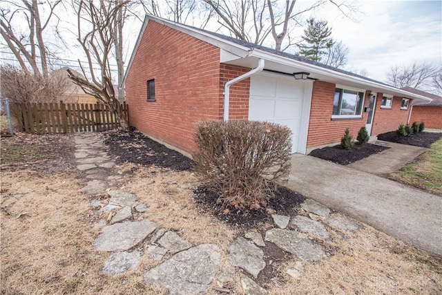 view of home's exterior featuring brick siding, fence, and an attached garage