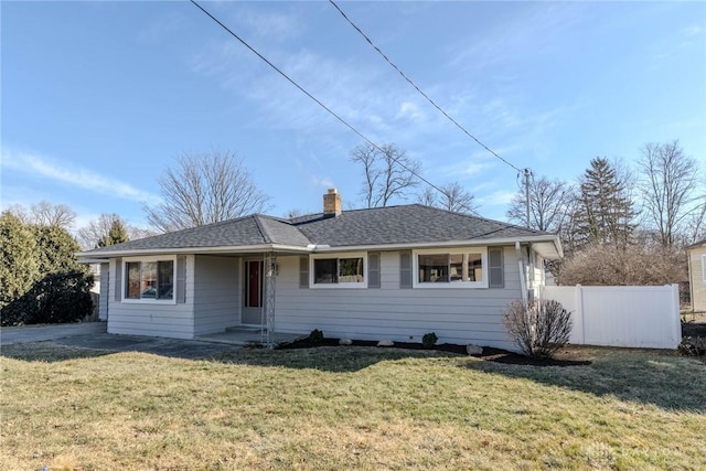 ranch-style home with a chimney, fence, a front lawn, and roof with shingles