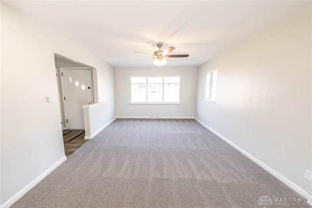 unfurnished room with dark carpet, baseboards, and ceiling fan