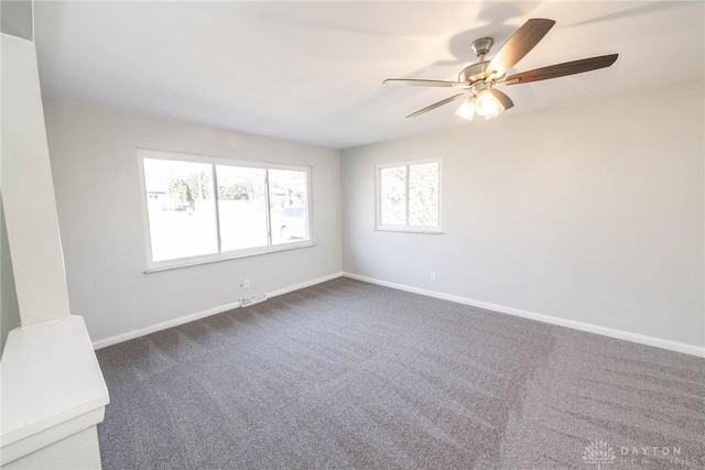 unfurnished room featuring baseboards, dark carpet, and ceiling fan