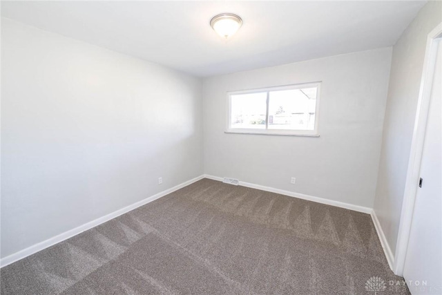 empty room with carpet, visible vents, and baseboards