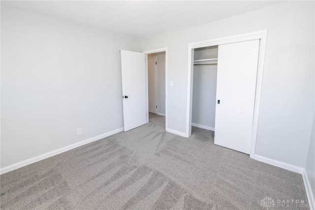 unfurnished bedroom featuring carpet, baseboards, and a closet