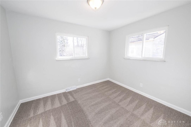 unfurnished room with baseboards, carpet floors, visible vents, and a healthy amount of sunlight