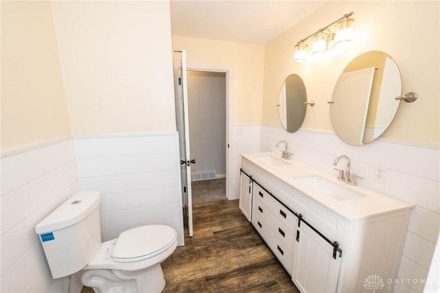 full bathroom with a wainscoted wall, a sink, visible vents, and toilet