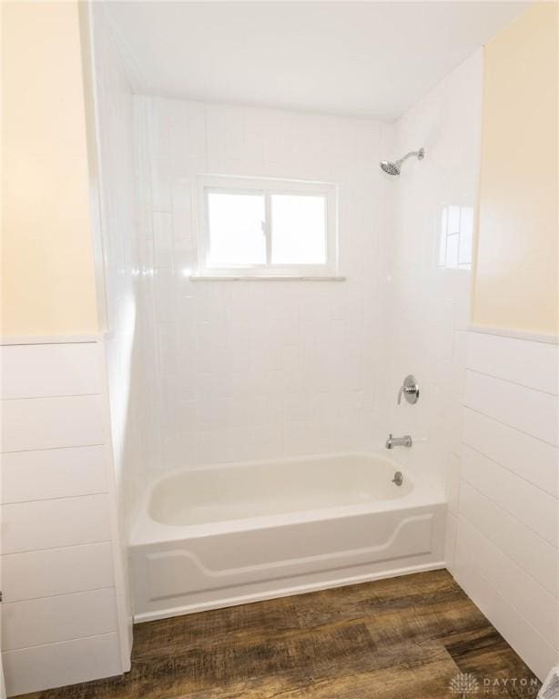 full bathroom featuring shower / washtub combination, wainscoting, and wood finished floors