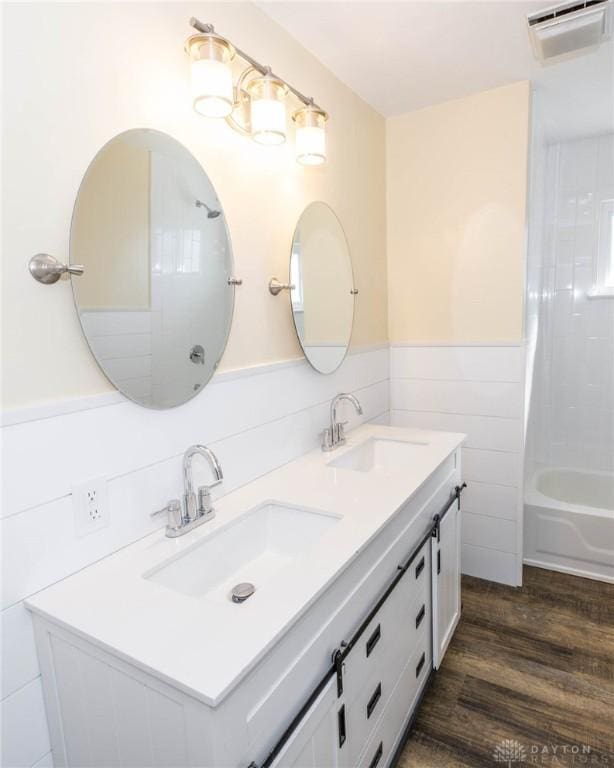 full bathroom featuring wood finished floors, tub / shower combination, a sink, and wainscoting