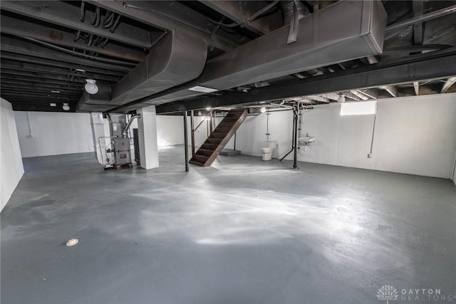 unfinished basement featuring stairs and heating unit