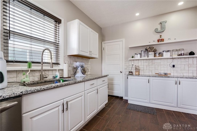 kitchen with white cabinets, a sink, light stone countertops, wood tiled floor, and backsplash