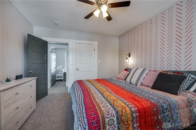 bedroom with an accent wall, dark colored carpet, a textured ceiling, and a ceiling fan