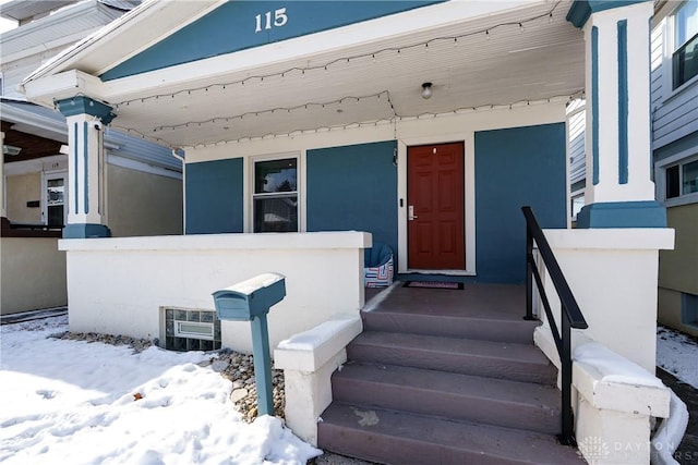 snow covered property entrance with stucco siding