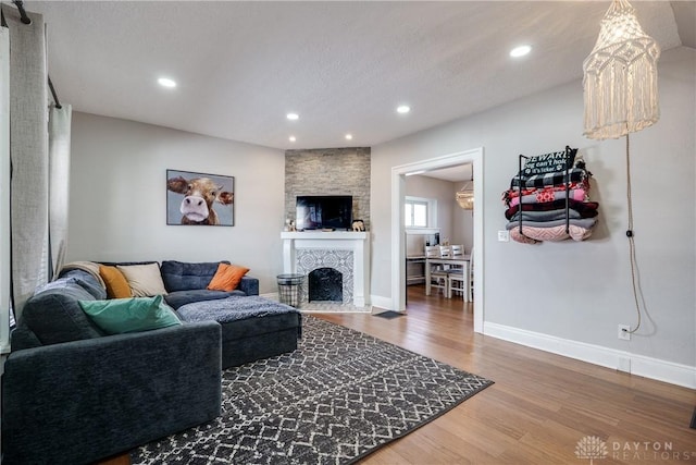 living area with recessed lighting, a fireplace, wood finished floors, and baseboards