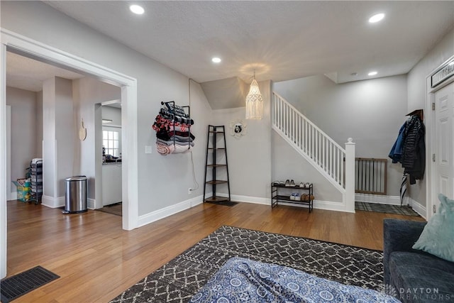 living area with recessed lighting, visible vents, wood finished floors, baseboards, and stairs