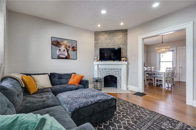 living room with recessed lighting, a fireplace, wood finished floors, visible vents, and baseboards