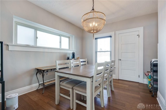 dining room with a notable chandelier, plenty of natural light, baseboards, and dark wood-style flooring