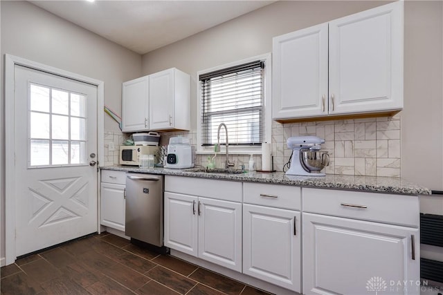 kitchen featuring light stone counters, white cabinets, a sink, and dishwasher