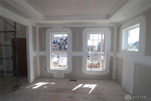 unfurnished dining area featuring a tray ceiling and visible vents
