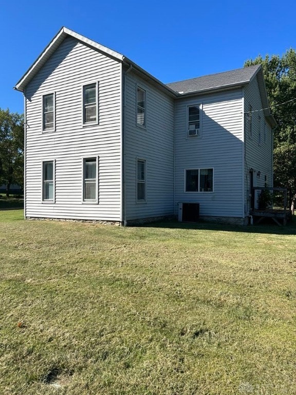 back of house featuring a lawn and central air condition unit