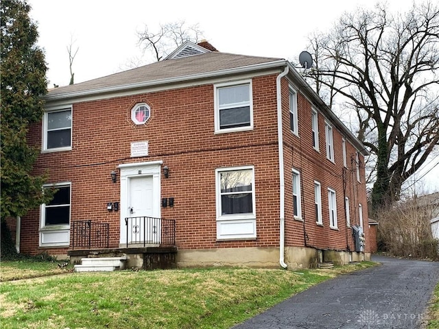 view of front facade with brick siding and a front lawn