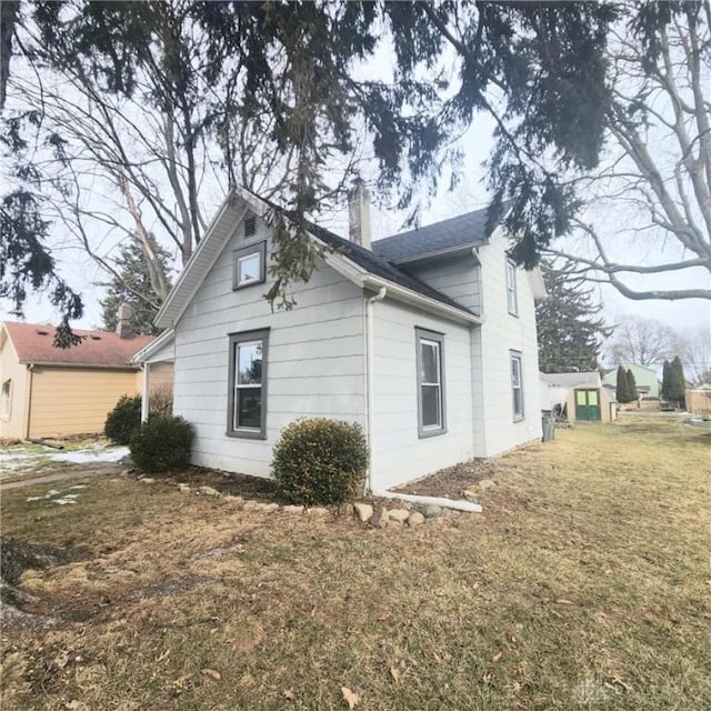 view of side of home with a chimney and a lawn