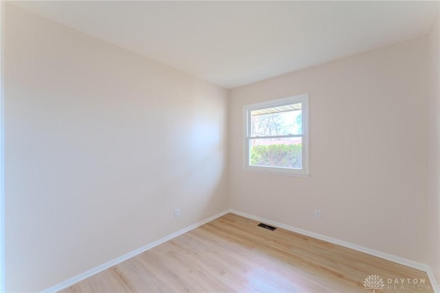 empty room with visible vents, light wood-style flooring, and baseboards