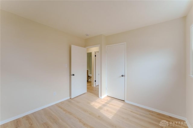 spare room with baseboards and light wood finished floors