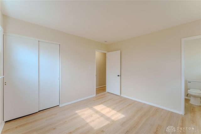 unfurnished bedroom featuring light wood-style floors, baseboards, and a closet