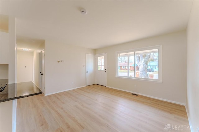 unfurnished living room with visible vents, light wood-style flooring, and baseboards