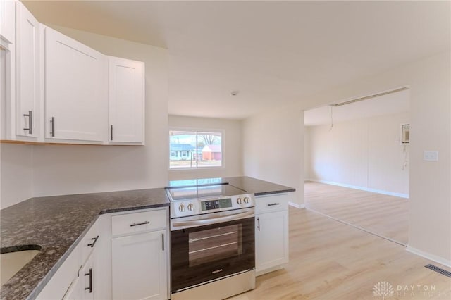 kitchen with dark stone counters, stainless steel range with electric stovetop, and white cabinets